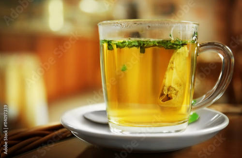 Glass cup of fresh green tea on blurred kitchen background