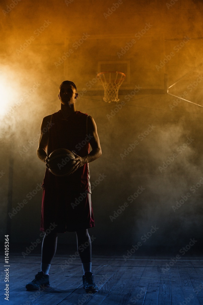 Fototapeta premium Portrait of a basketball player holding a ball in his hands