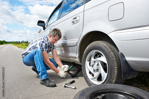 Man changing a spare tire of car