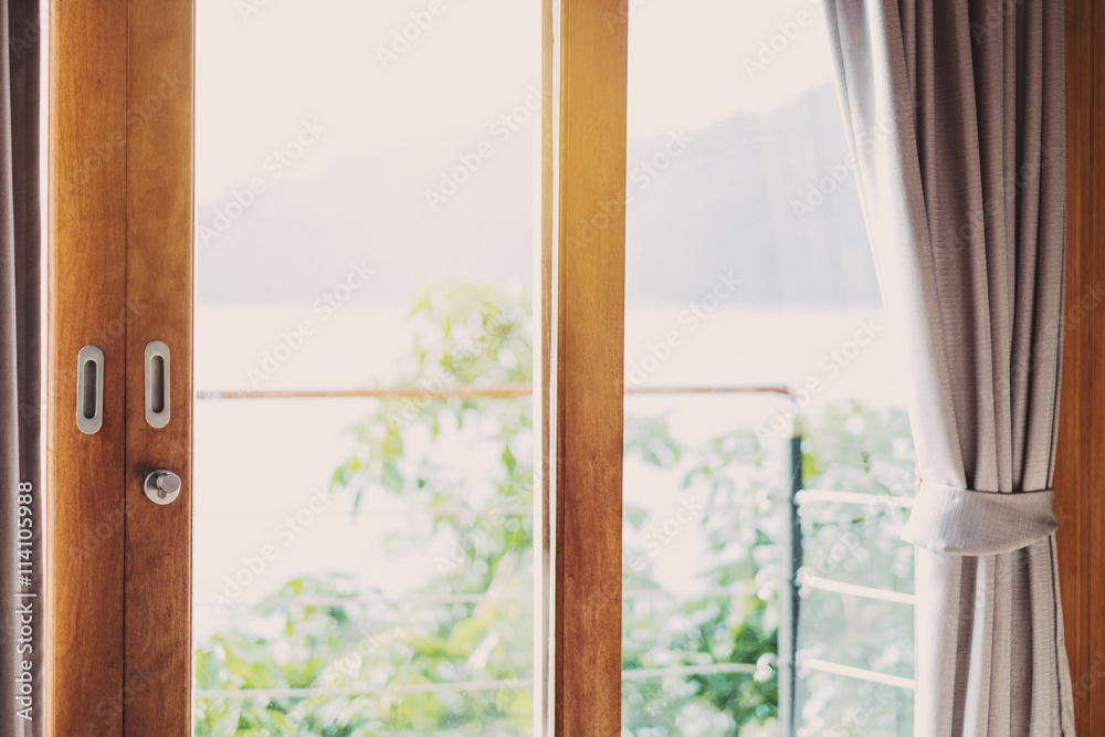 Wooden balcony door frame with curtain in the morning, with bright light, vintage tone Wooden balcony door frame with curtain in the morning, with bright light, vintage tone