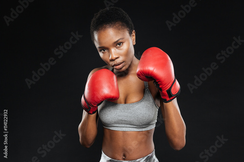 Fitness girl in boxing gloves fighting on black background