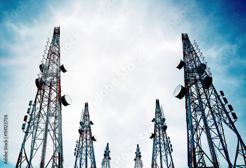 Telecommunication towers with TV antennas and satellite dish on clear blue sky