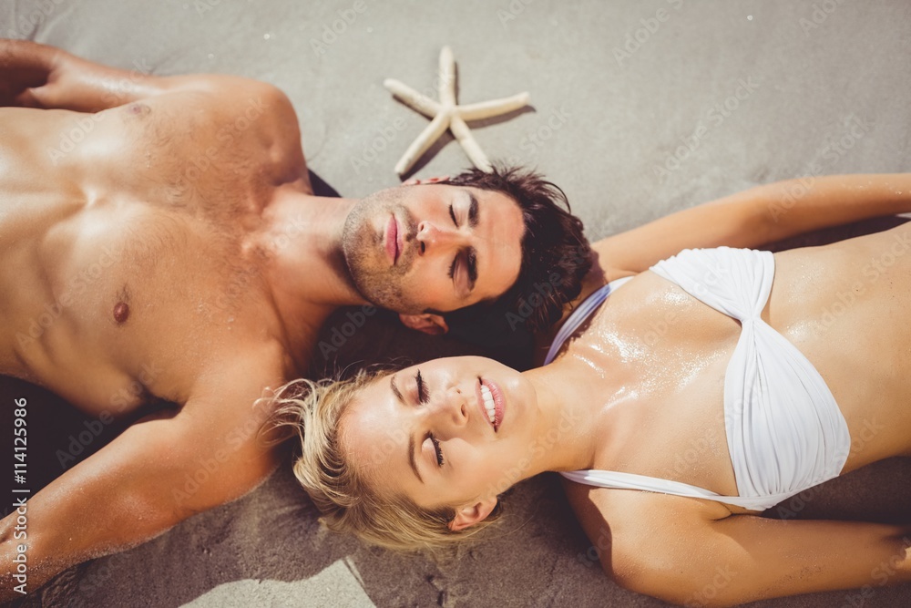 Couple lying on beach - obrazy, fototapety, plakaty 