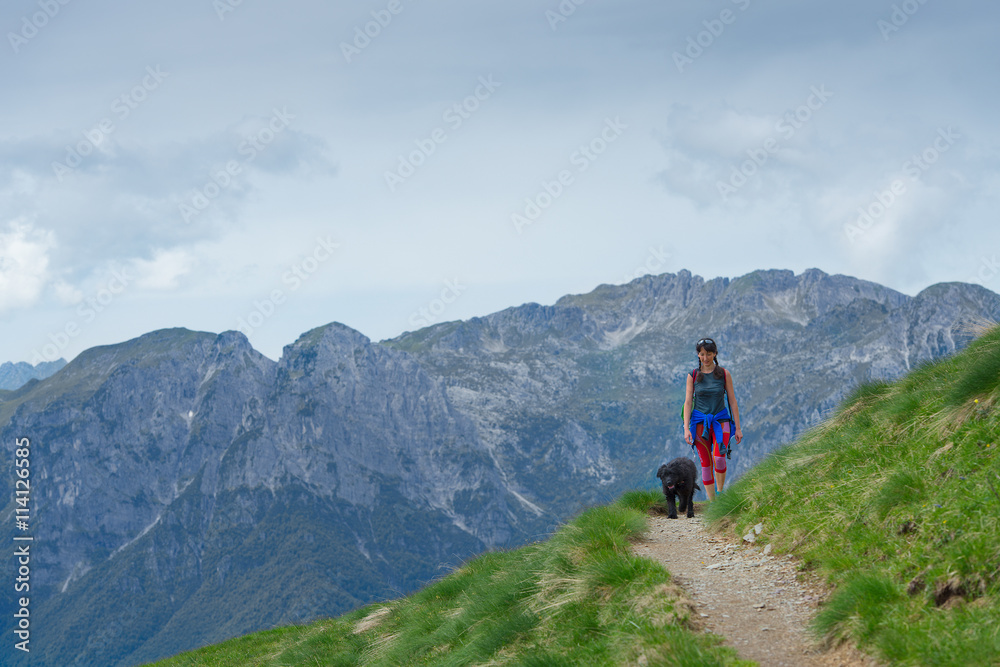 Woman with her dog walking on the mountain path