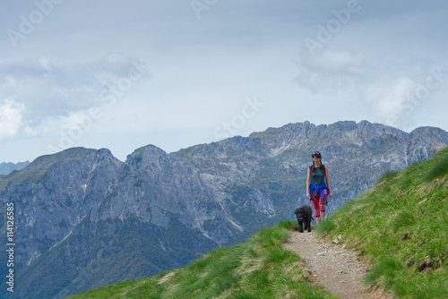 Woman with her dog walking on the mountain path