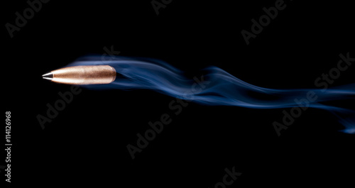 Bullet flying across a black background with smoke behind after a shooting