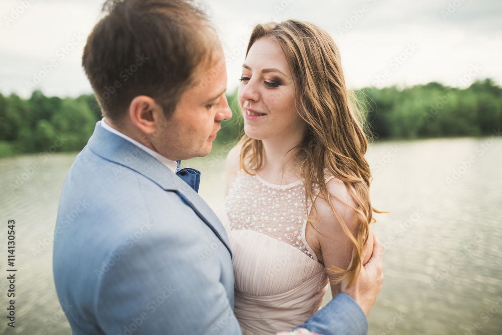 Bride and groom holding beautiful wedding bouquet. Lake, forest