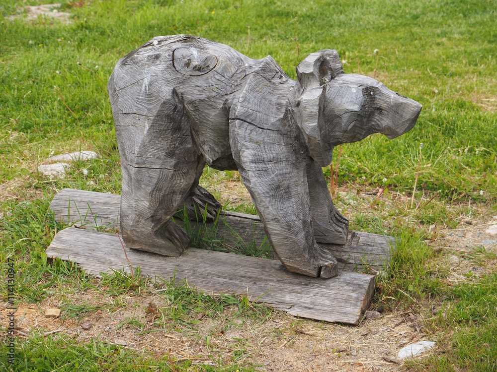 wooden figurine of a bear on the grass