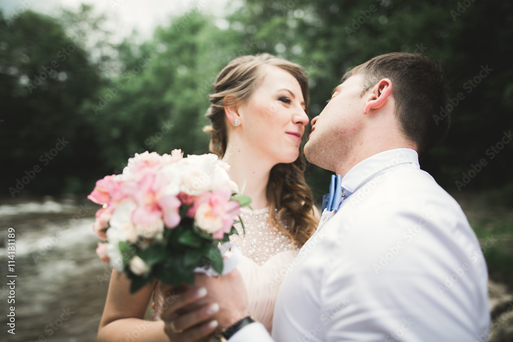 Elegant gentle stylish groom and bride near river with stones. Wedding couple in love Elegant gentle stylish groom and bride near river with stones. Wedding couple in love