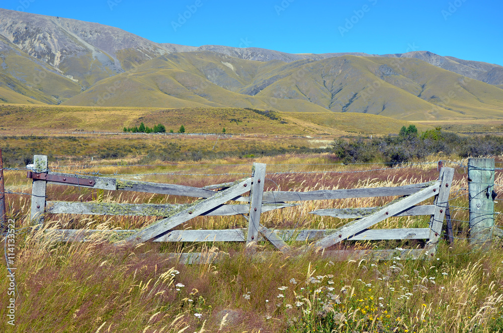 Rustic wooden gate in a meadow with mountains in the distance