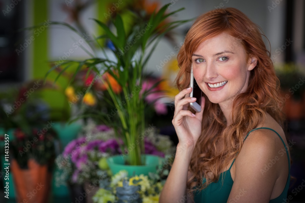 Female florist talking on mobile phone in flower shop Female florist talking on mobile phone in flower shop