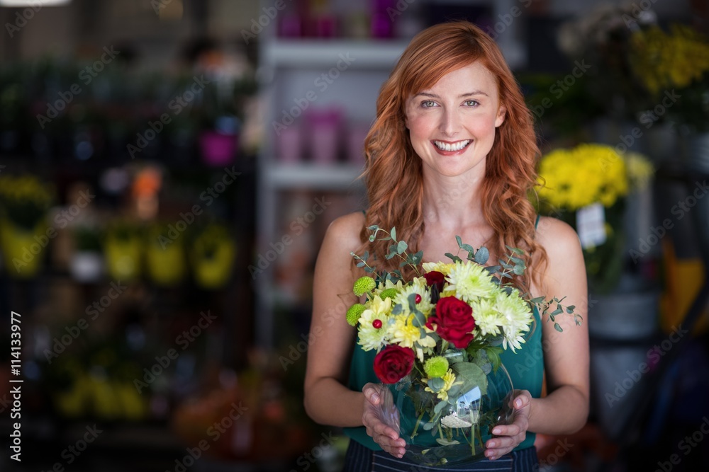 Female florist holding flower vase at flower shop