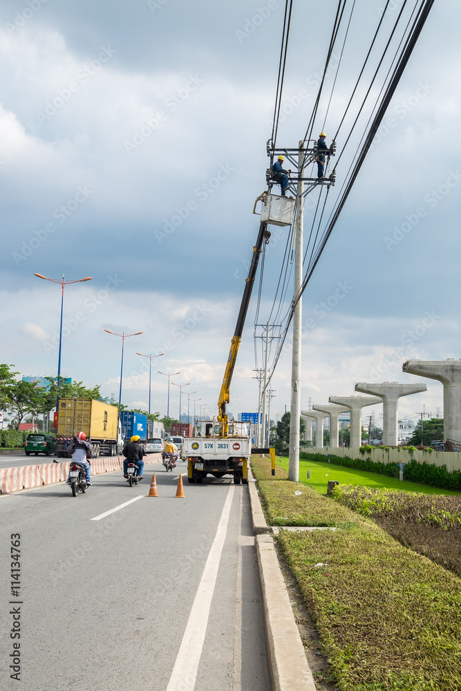 Ho Chi Minh, Vietnam - June 21, 2016: Construction Electrician lineman repairman worker on the crane truck, going around to check, fix and construct the new line electricity. Ho Chi Minh, Vietnam - June 21, 2016: Construction Electrician lineman repairman worker on the crane truck, going around to check, fix and construct the new line electricity.