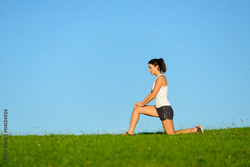 Sporty woman warming up knee before running or exercising outdoor. Runner joint care for workout. Sporty woman warming up knee before running or exercising outdoor. Runner joint care for workout.