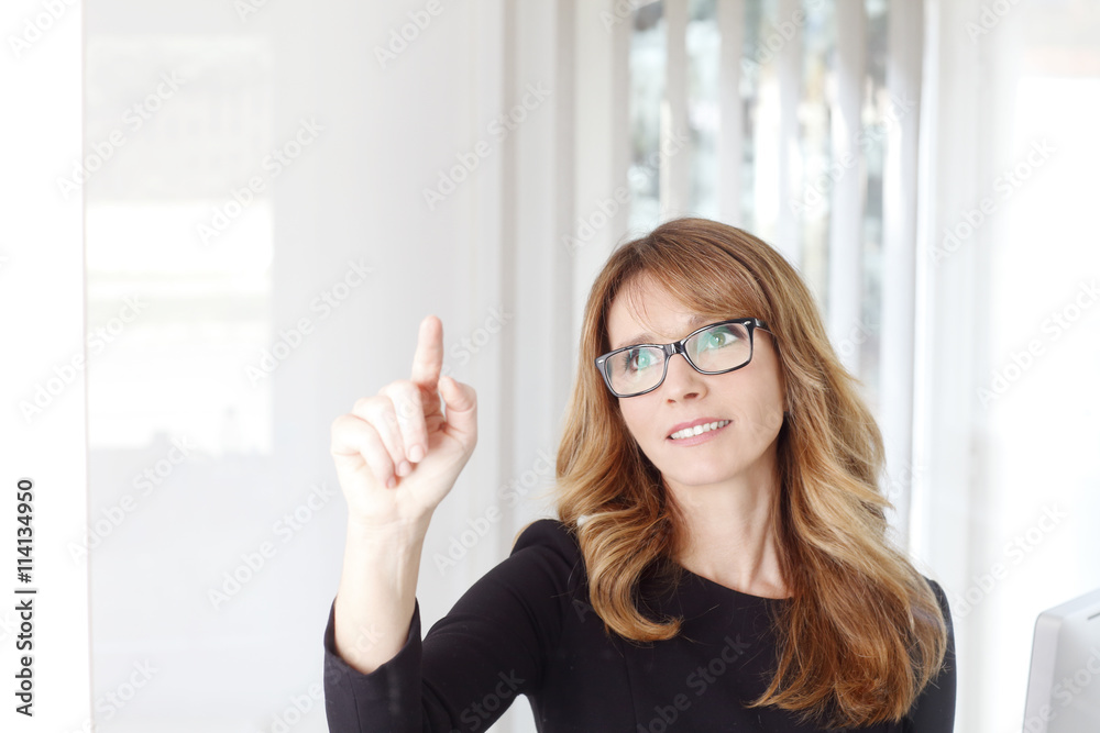 Atractive professional business woman standing at office behind a virtual screen Atractive professional business woman standing at office behind a virtual screen