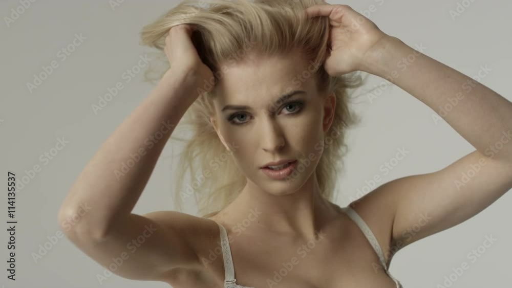 Portrait of a beautiful sexy blonde woman wearing white underwear. Attractive woman posing in studio over gray background. Lingerie/fashion concept. Portrait of a beautiful sexy blonde woman wearing white underwear. Attractive woman posing in studio over gray background. Lingerie/fashion concept.