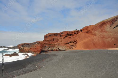rote Lava-Felsen und schwarzer Sand an Küste der spanischen Vulkaninsel Lanzarote