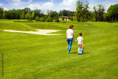 Mother teaching son to play golf