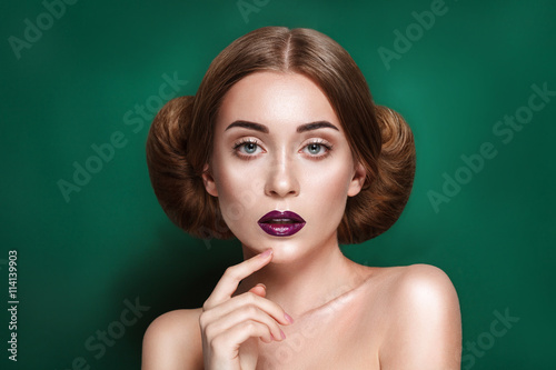 Attractive mysterious young woman with double hair bun in Princess Leia hairstyle looks towards the camera