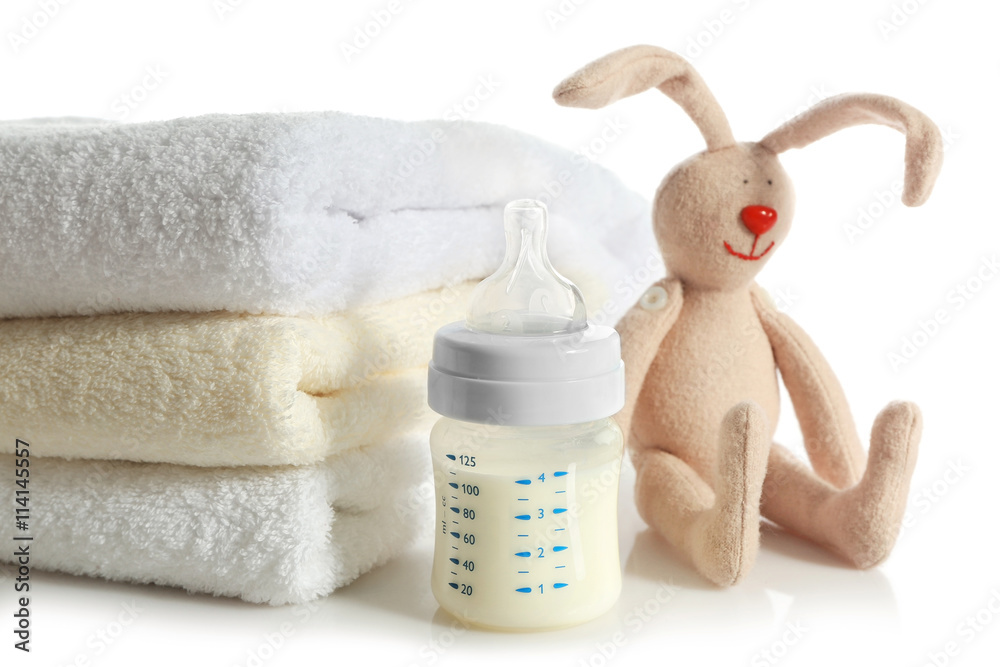 Φωτογραφία Baby bottle with milk, pile of soft towels and rabbit toy isolated on white