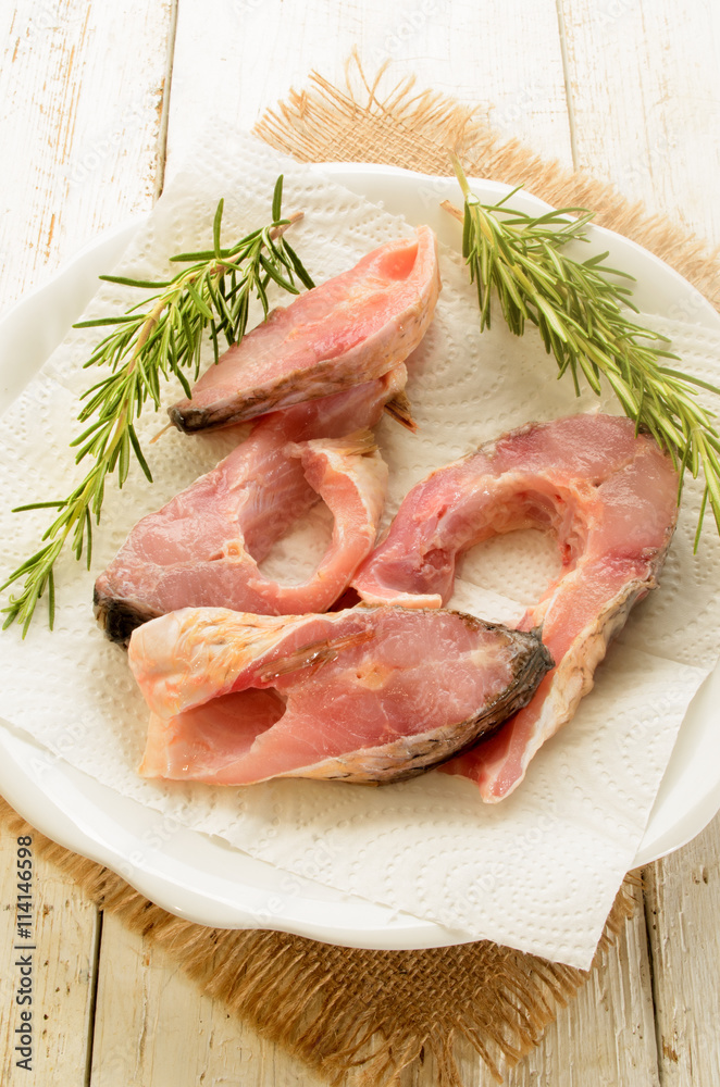 raw carp steak with paper kitchen towel and rosemary raw carp steak with paper kitchen towel and rosemary