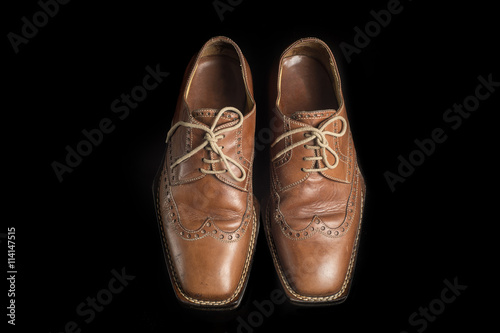 pair of brown leather shoes isolated on a black background
