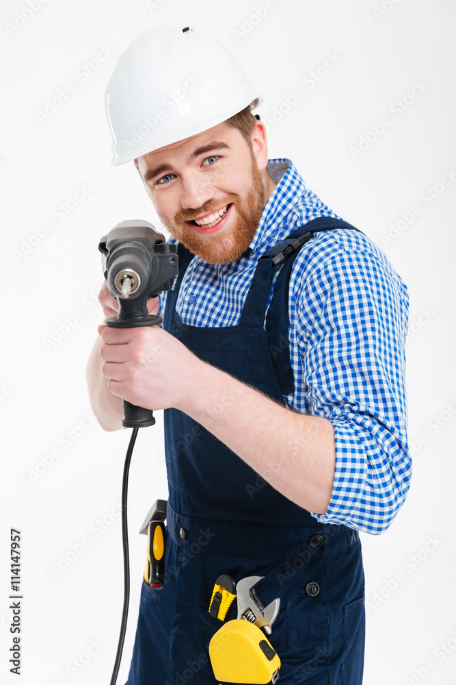 Smiling bearded young man using drill and pointing on you Smiling bearded young man using drill and pointing on you
