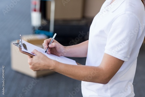 Close up of delivery woman is writing on a clipboard