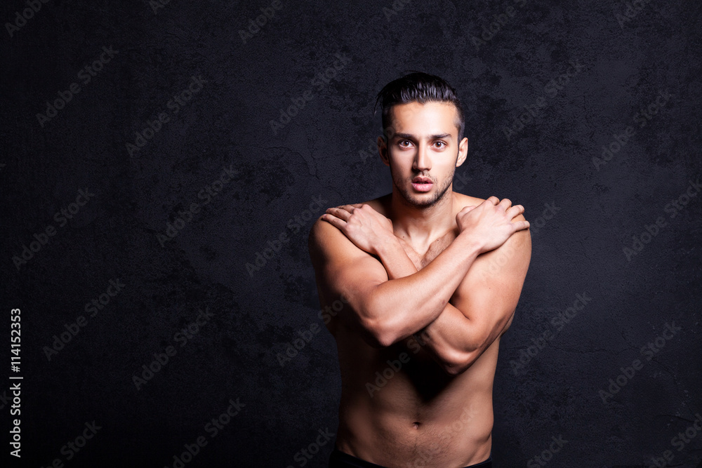 Fototapeta premium Sexy shirtless male model flirting against black background