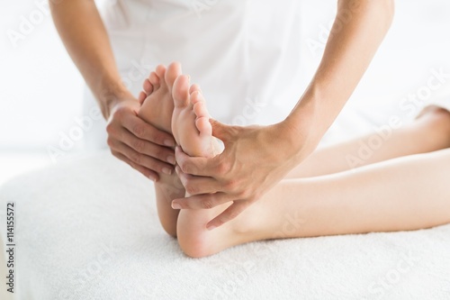 Cropped image of masseur giving foot massage to woman 