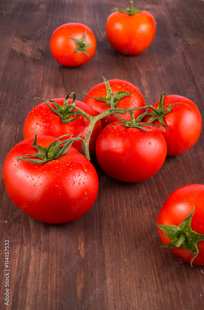Ripe fresh tomatoes on a branch on a wooden table. Ripe fresh tomatoes on a branch on a wooden table.
