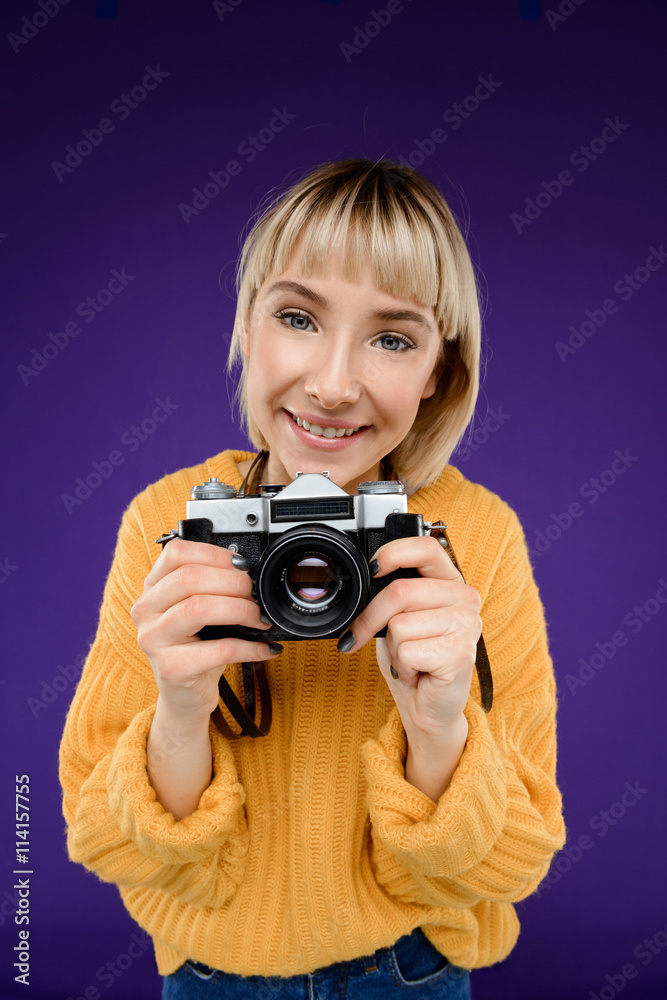 Portrait of young girl with camera over purple background. Portrait of young girl with camera over purple background.