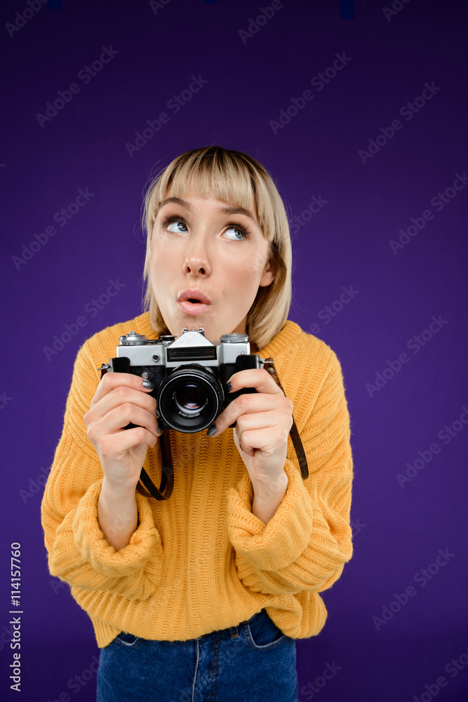 Portrait of young girl with camera over purple background. Portrait of young girl with camera over purple background.