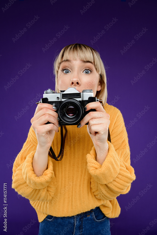 Portrait of young girl with camera over purple background. Portrait of young girl with camera over purple background.