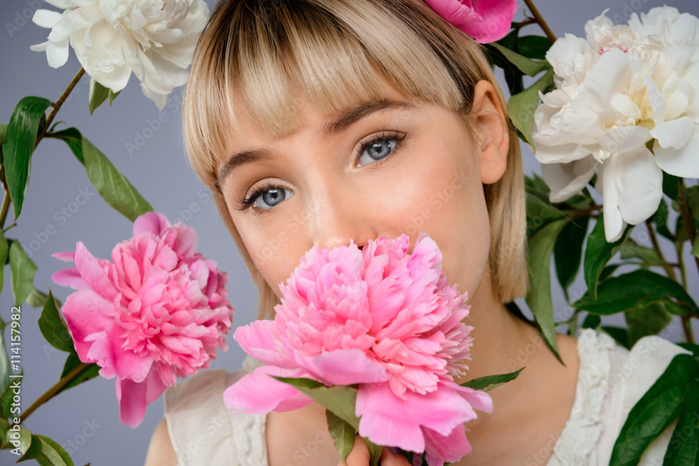 Portrait of young girl among flowers over grey background. Portrait of young girl among flowers over grey background.
