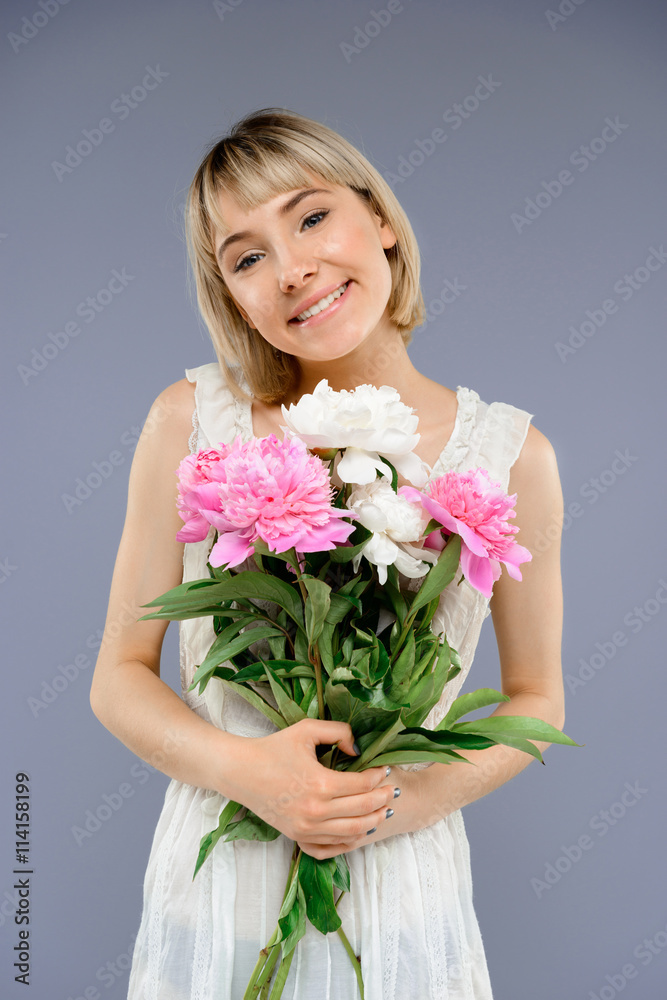 Portrait young girl with bouquet of flowers over grey backgro