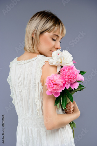 Portrait young girl with bouquet of flowers over grey backgro