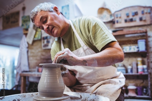 Craftsperson making container in pottery workshop photo
