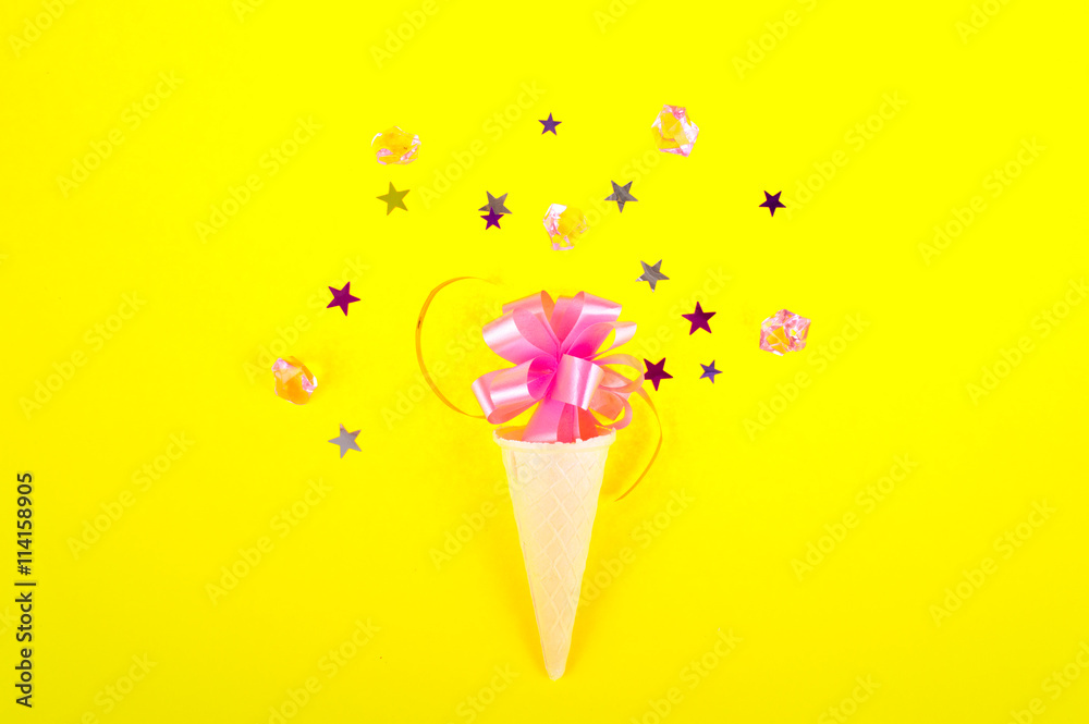 Ice cream cone with colorful party streamers on pink background. Flat lay Ice cream cone with colorful party streamers on pink background. Flat lay