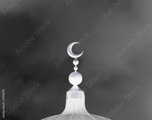 White slamic symbol on mosque’s cupola on dark cloudy backgrounds photo