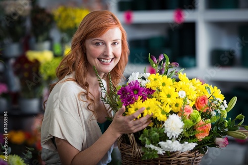 Happy female florist holding basket of flowers © WavebreakmediaMicro