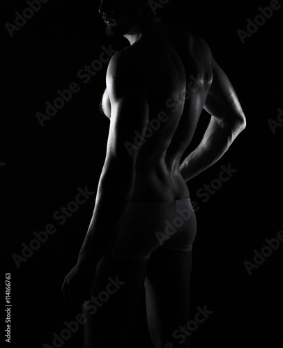 beautiful men s sporty body in backlight on the black background