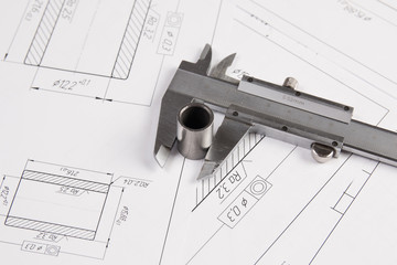 Metal cylinders and calipers on printed engineering drawings. Mechanics and Engineering Technology. Engineering drawings of steel parts