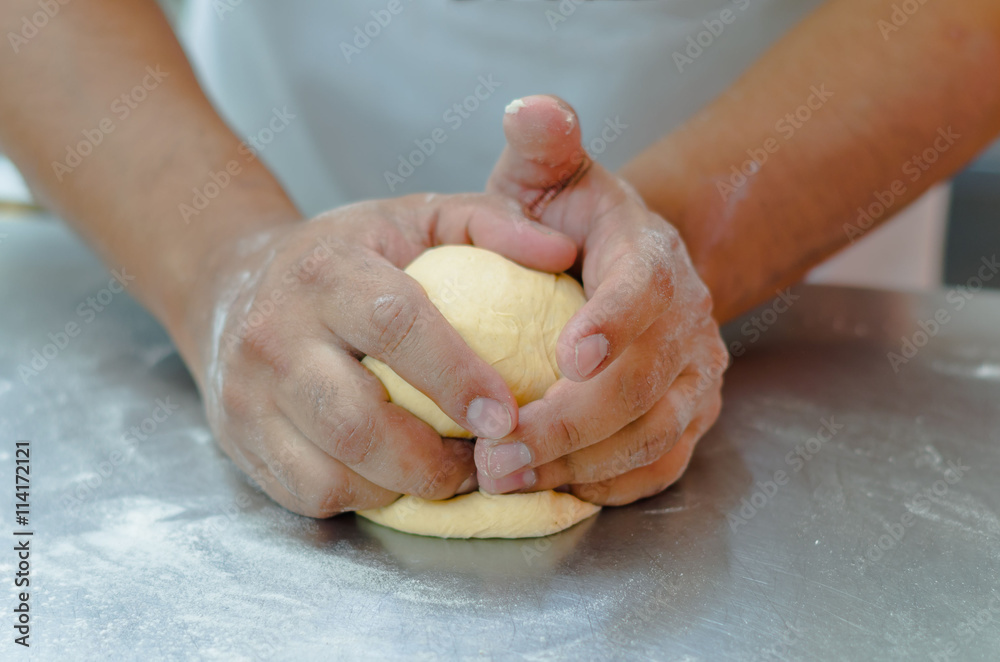 Bakers hands working and kneading bread dough on metal surface