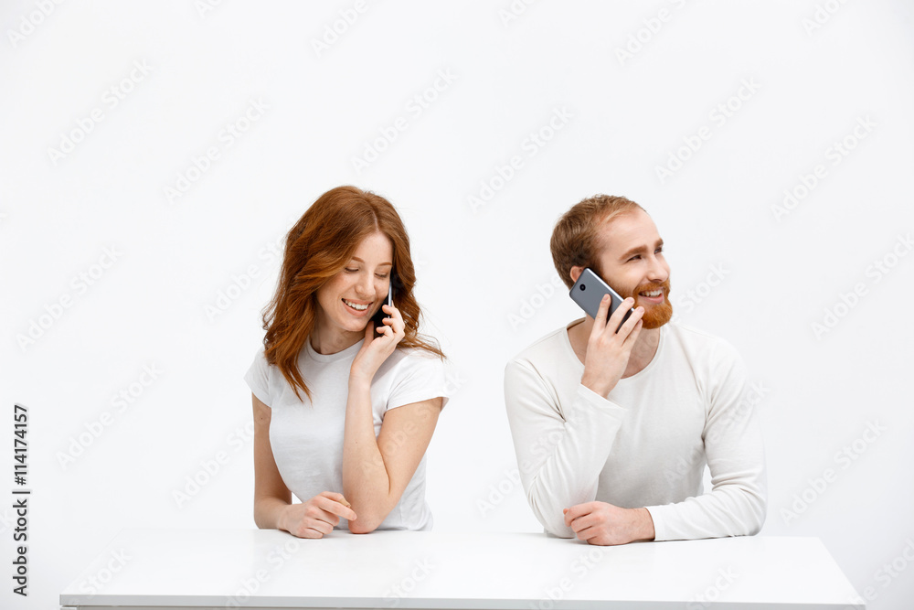 Tenderless redhead girl and boy talking on phones sitting at Tenderless redhead girl and boy talking on phones sitting at