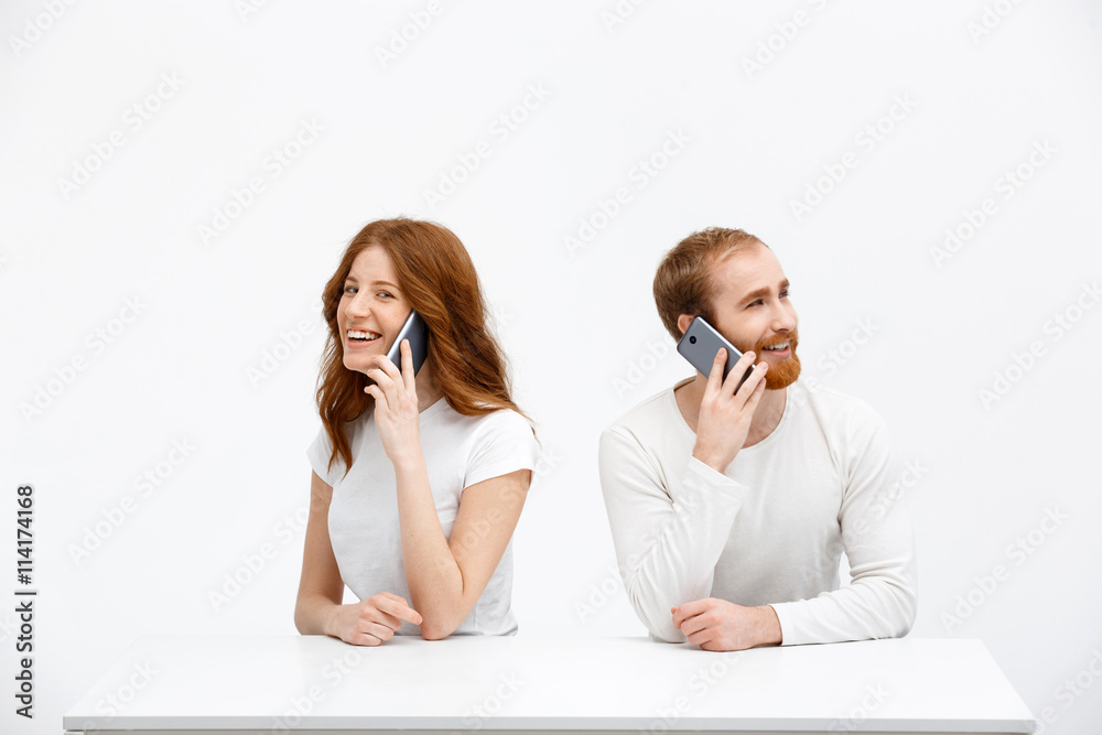 Tenderless redhead girl and boy talking on phones sitting at Tenderless redhead girl and boy talking on phones sitting at