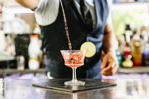 Barman is making cocktail at night club.