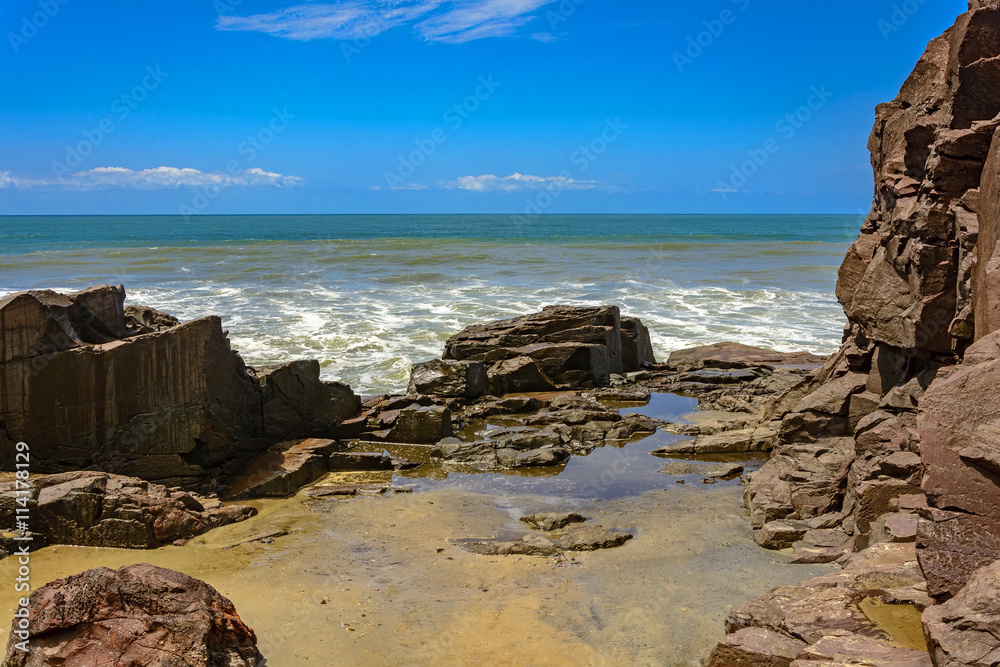 Rock formation in front of the sea with horizon and blue sky