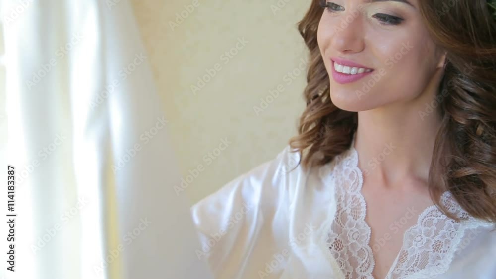 Happy bridge touches wedding dress near the window Happy bridge touches wedding dress near the window