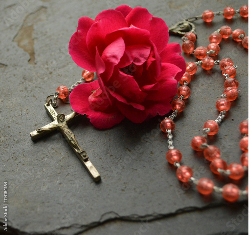 Pink rosary beads on stone with rose